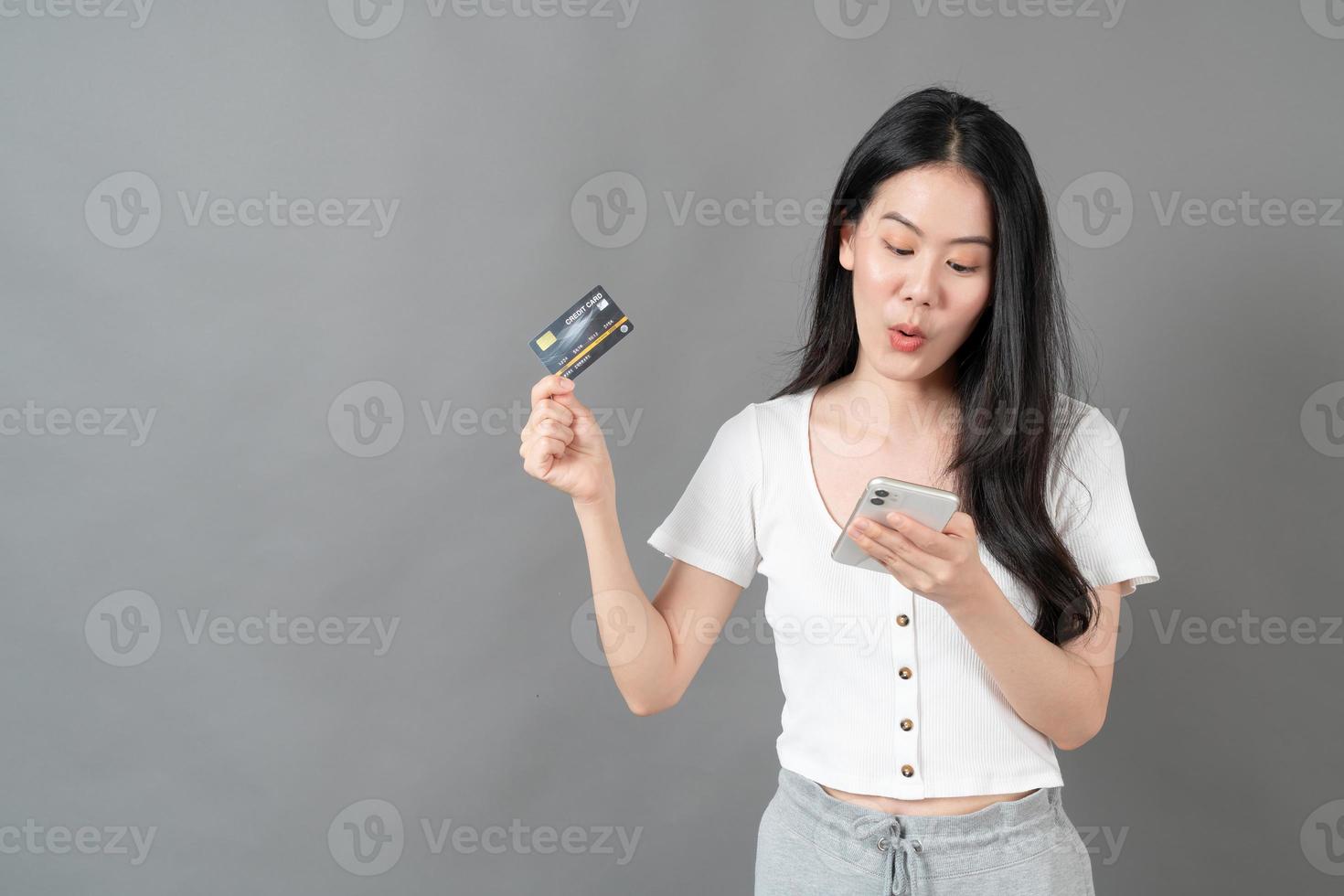jonge aziatische vrouw die telefoon met de hand met creditcard gebruikt - online winkelconcept foto