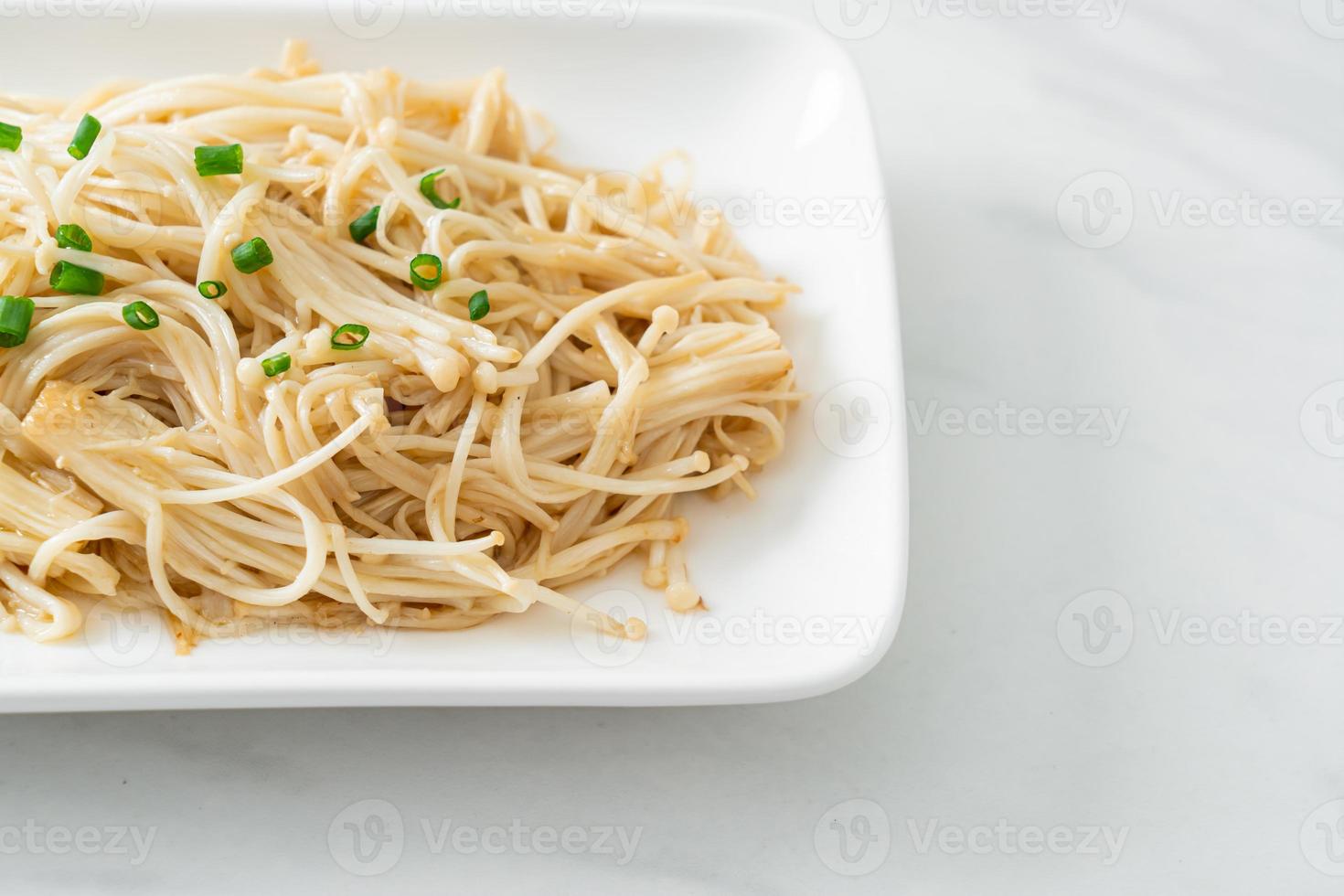 geroerbakte gouden naaldpaddestoel met boter op witte plaat foto