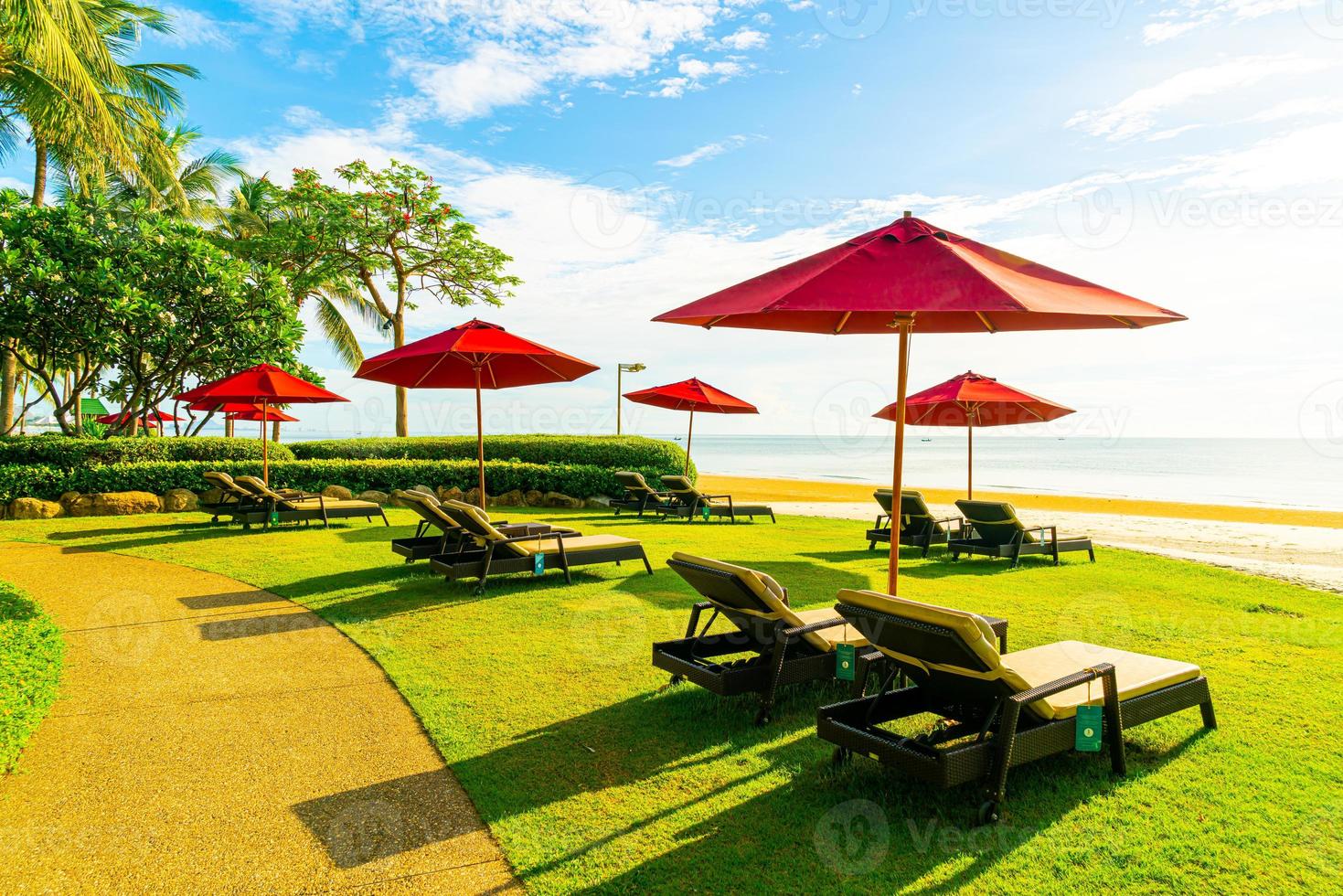 rode paraplu en strandstoel met zee strand achtergrond en blauwe lucht en zonlicht foto