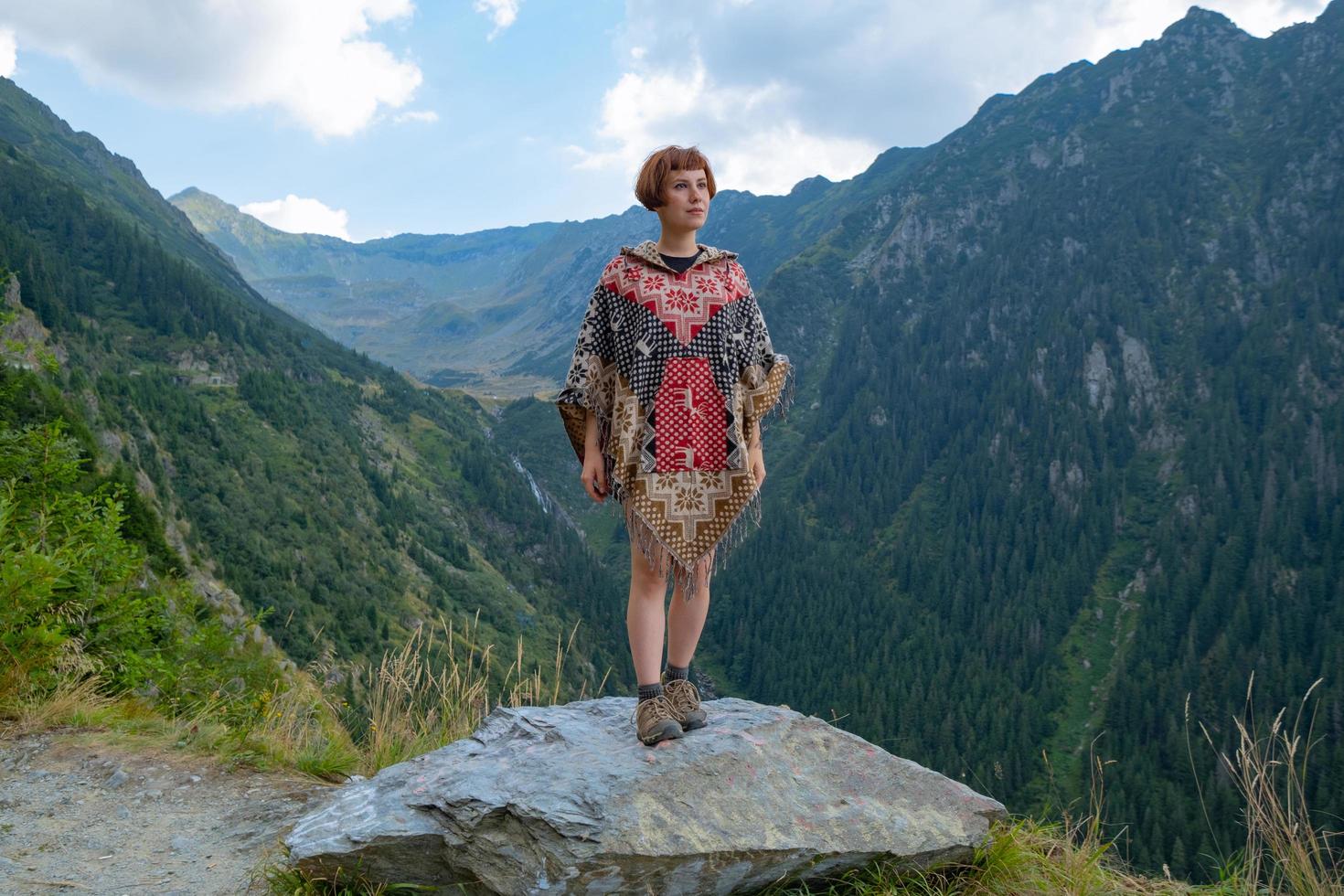vrouwelijke reiziger in poncho poseren in de bergen foto