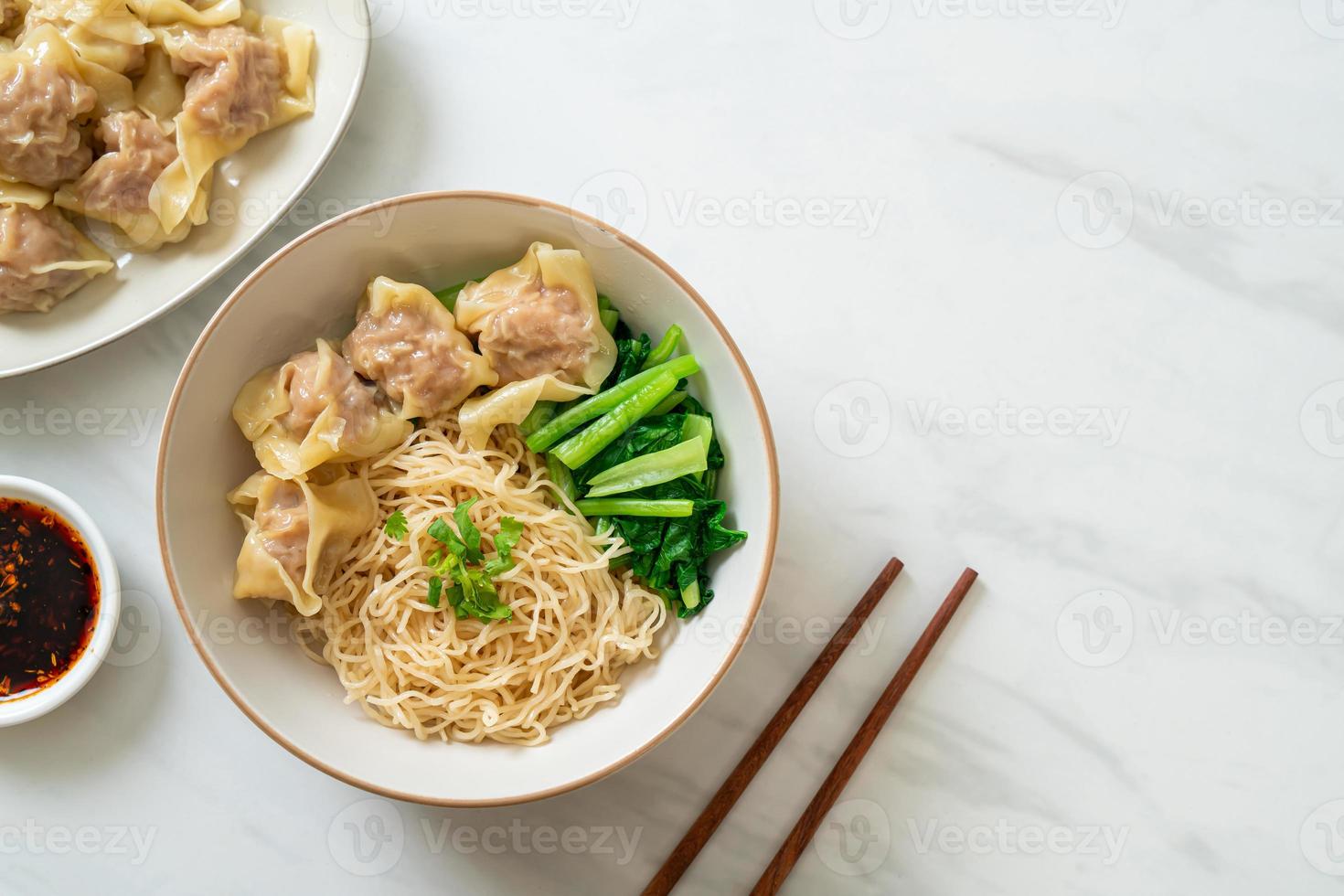 gedroogde eiernoedels met wonton van varkensvlees of dumplings van varkensvlees zonder soep in Aziatische stijl foto