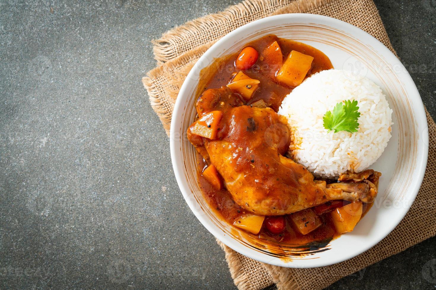 zelfgemaakte kipstoofpot met tomaten, uien, wortel en aardappelen op bord met rijst foto