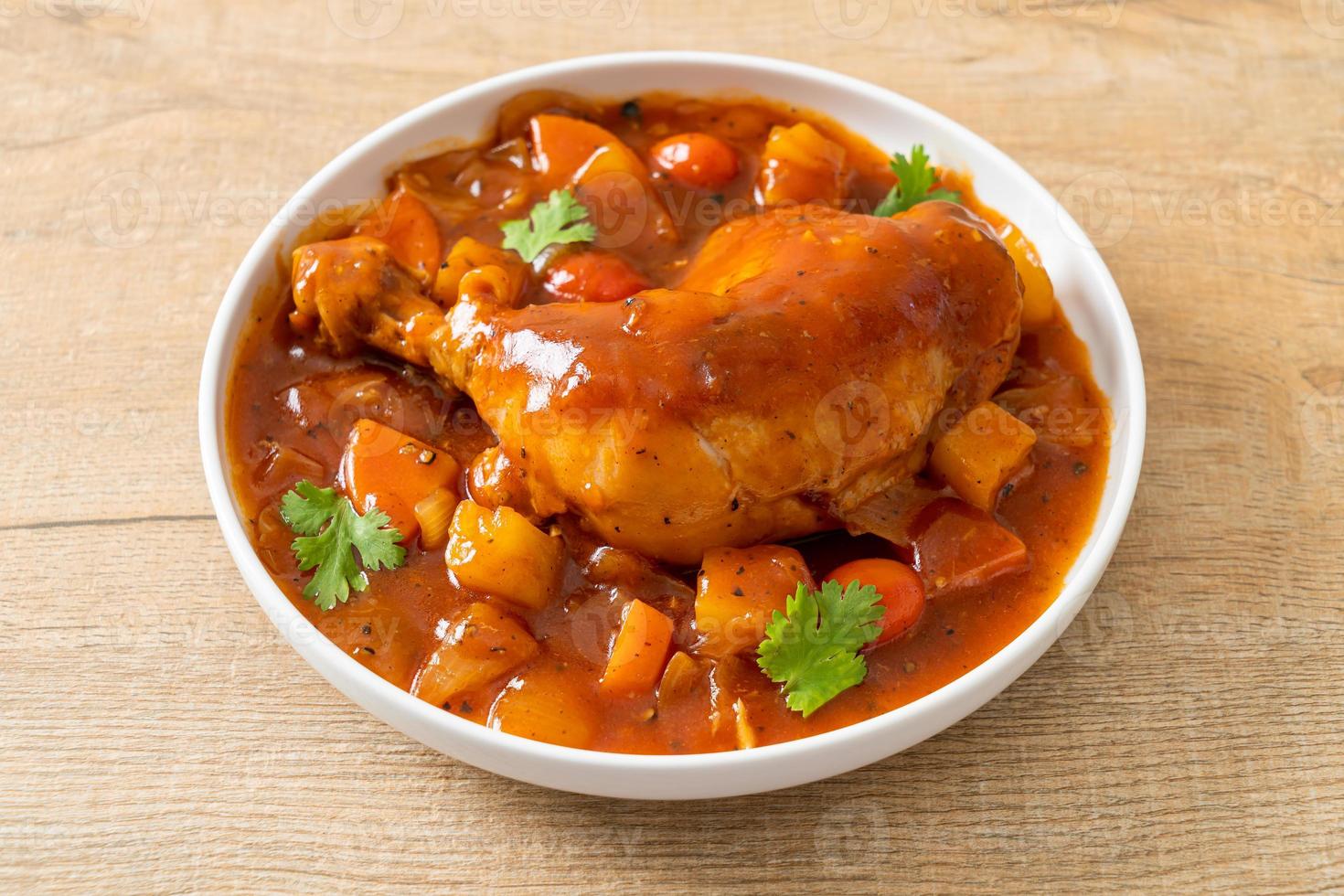 huisgemaakte kippenstoofpot met tomaten, uien, wortel en aardappelen op bord foto