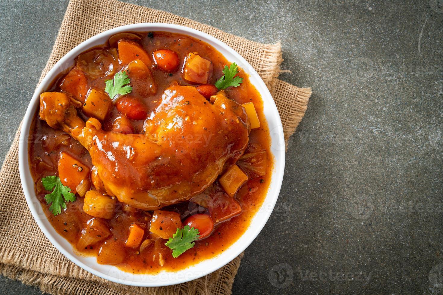 huisgemaakte kippenstoofpot met tomaten, uien, wortel en aardappelen op bord foto