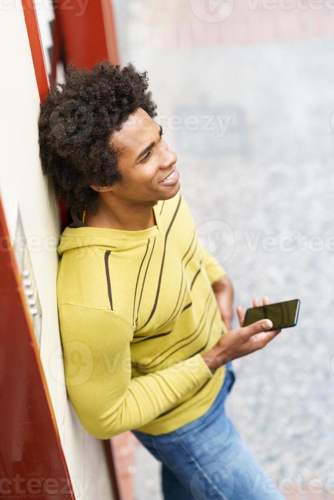 zwarte man met afrohaar en koptelefoon met smartphone. foto