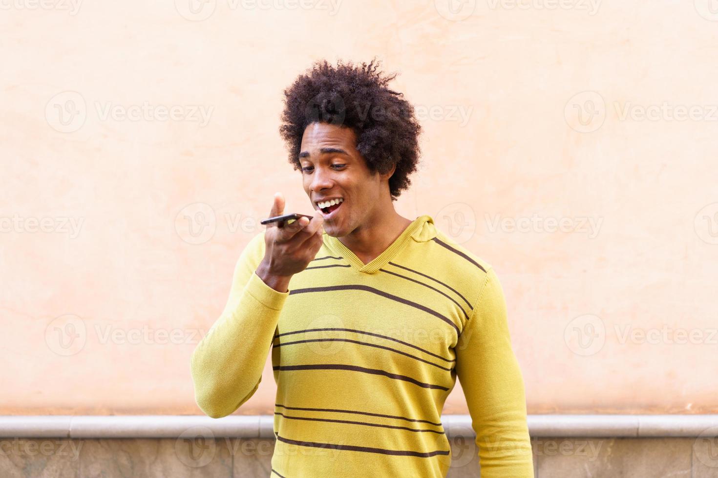 zwarte man met afrohaar en koptelefoon met smartphone. foto