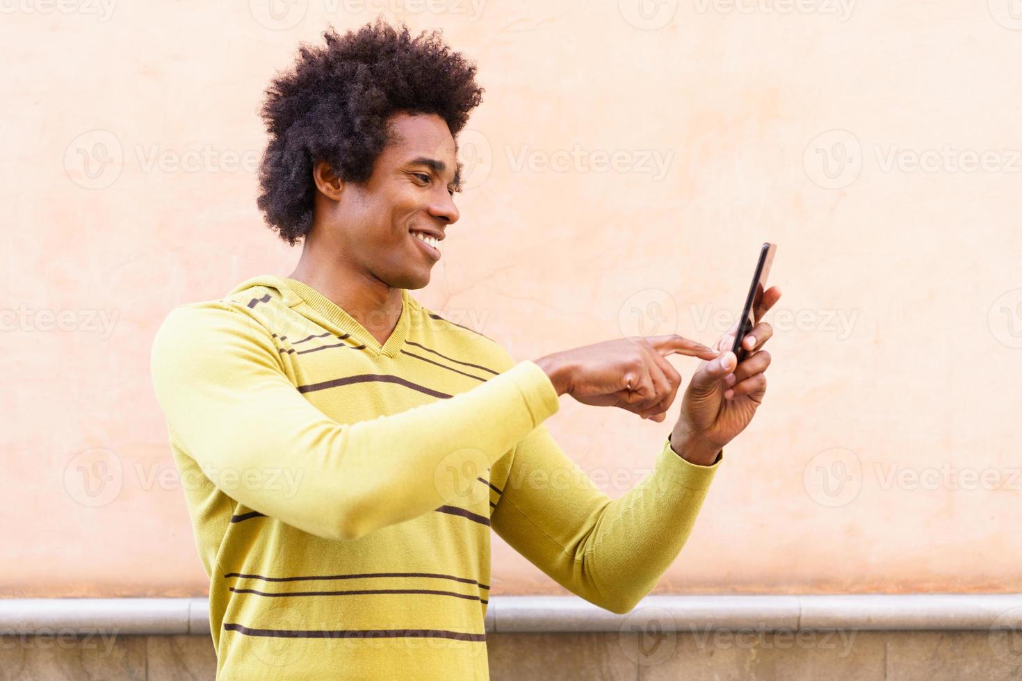 zwarte man met afrohaar en koptelefoon met smartphone. foto