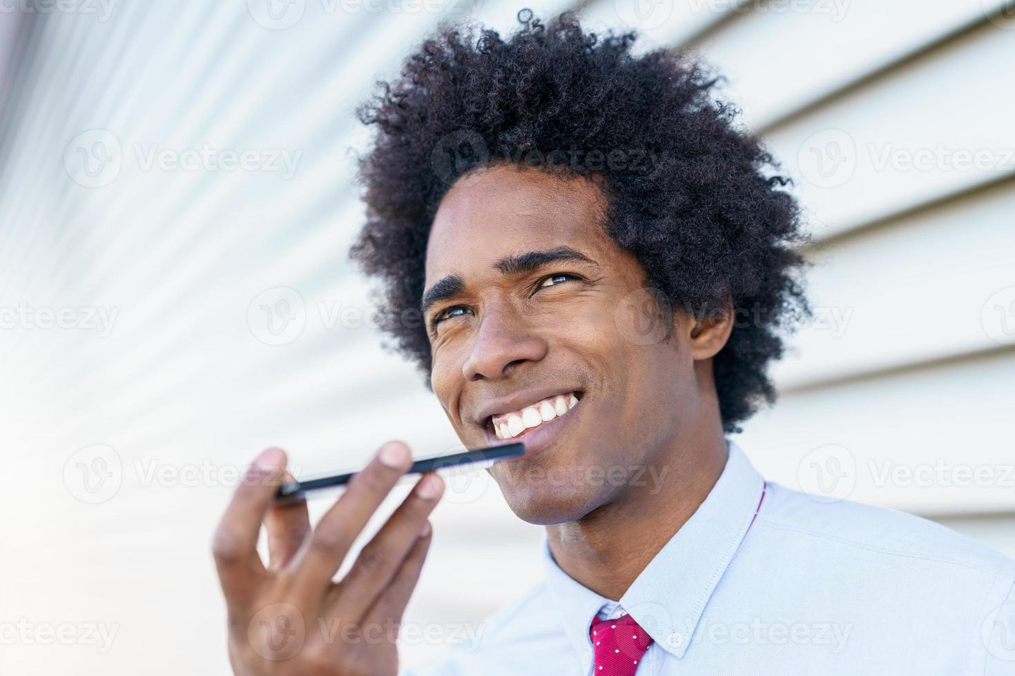 zwarte zakenman die een smartphone gebruikt in de buurt van een kantoorgebouw foto