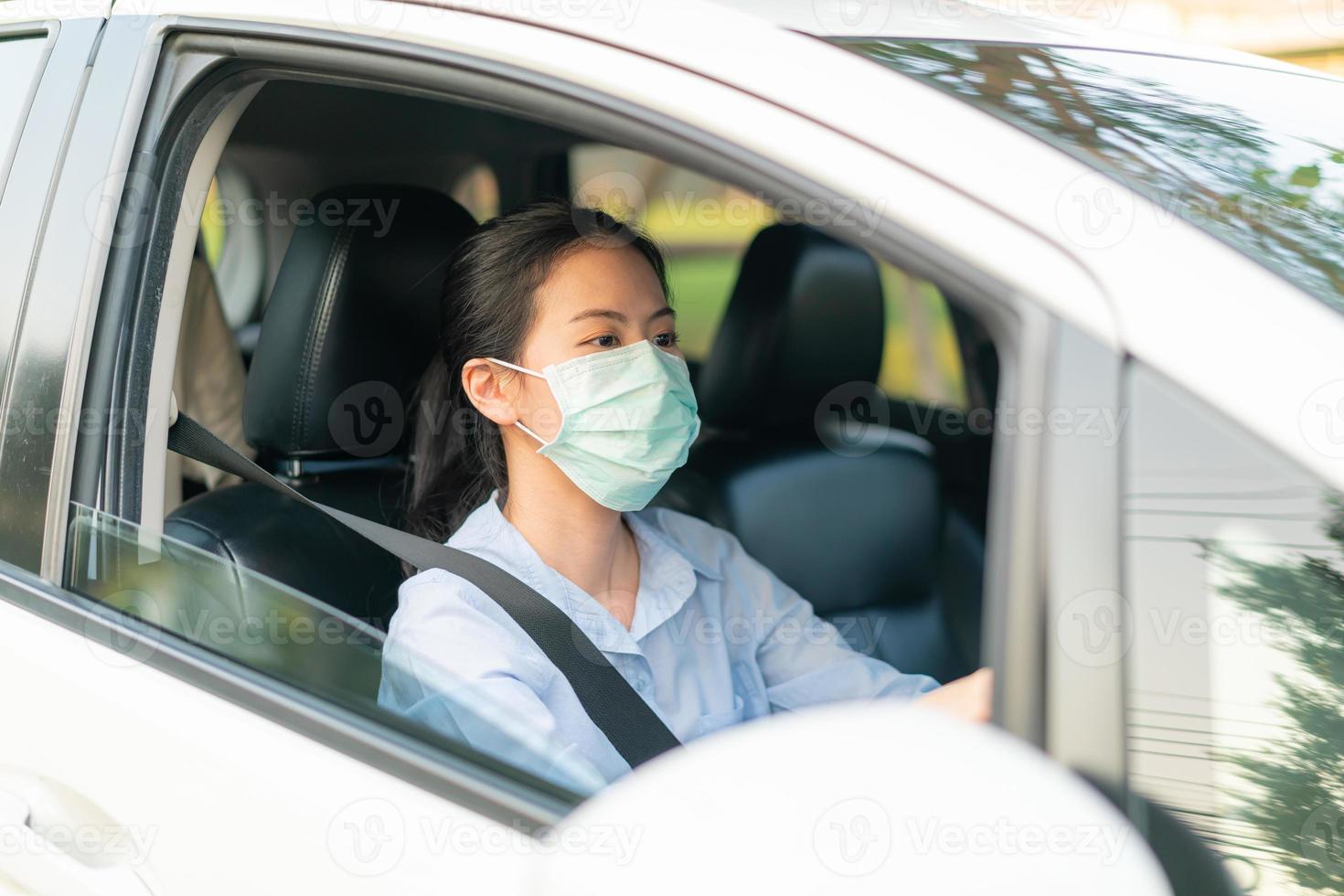 mooie aziatische vrouw die auto rijdt met een gezichtsmasker naar buiten blijf gezond beschermend tegen het coronavirus covid-19 virus foto