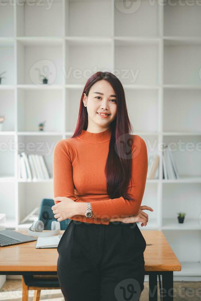 geslaagd zakenvrouw staand in creatief kantoor en op zoek Bij camera. vrouw ondernemer in een coworking ruimte lachend. foto