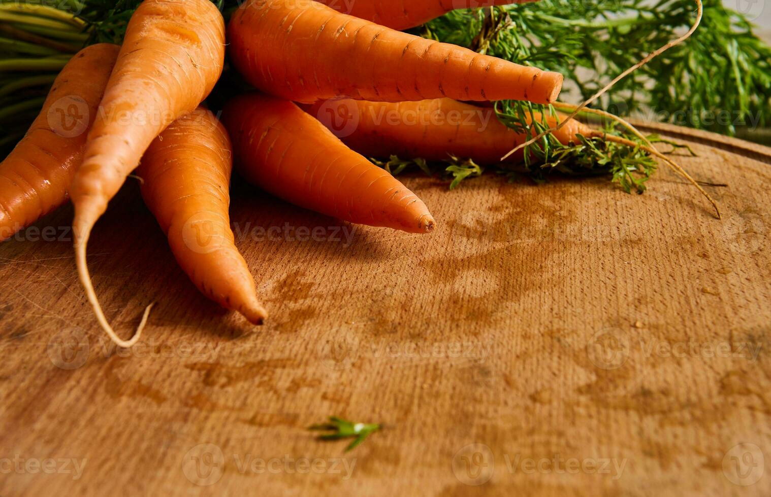 detailopname van een groot bundel van vers wortels met groen tops en bladeren Aan een houten snijdend bord . voedsel achtergrond van seizoensgebonden rauw groenten. kopiëren advertentie ruimte foto