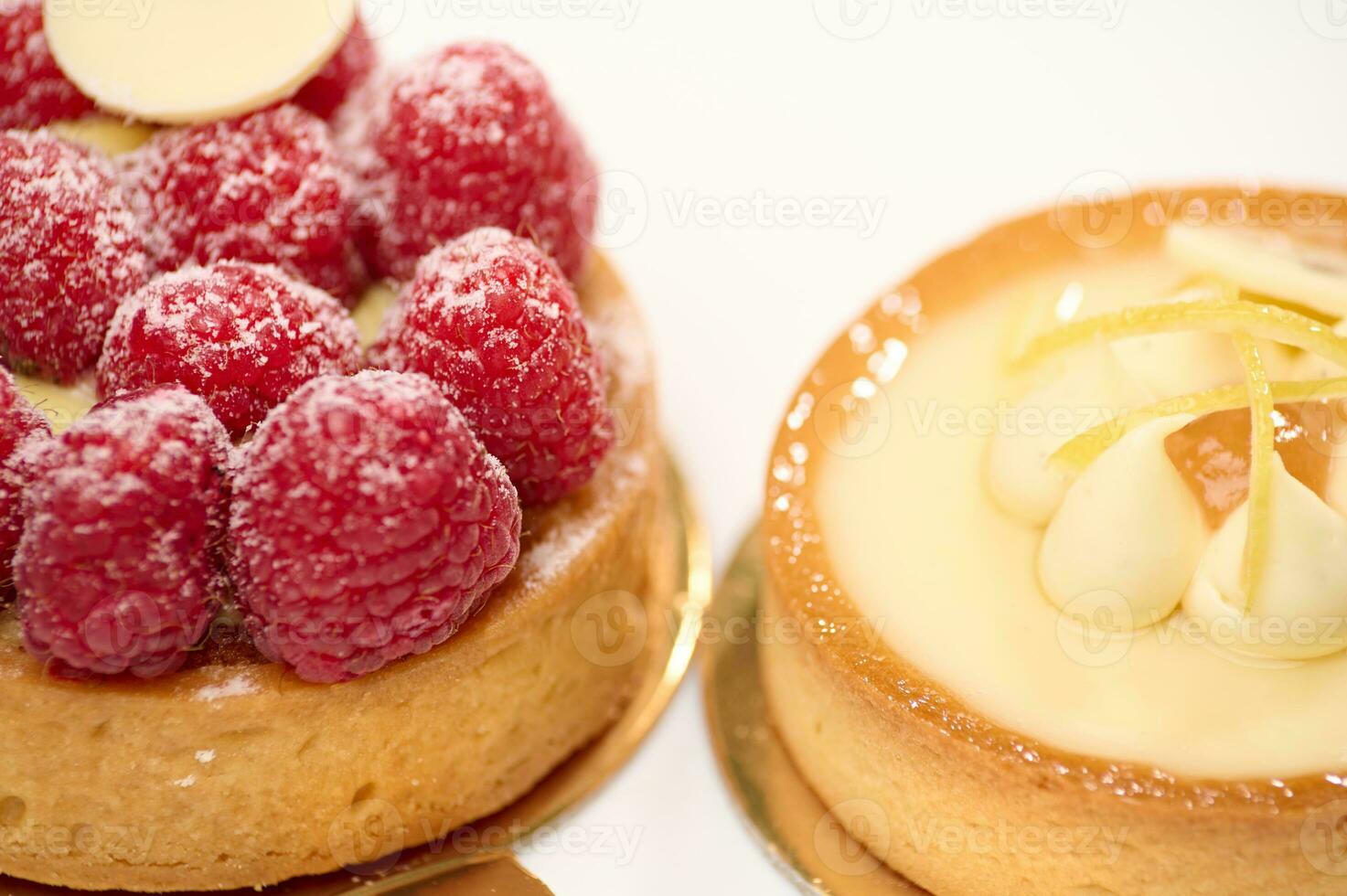 detailopname visie van Frans desserts - een citroen en framboos schuimgebak taart en taartje Aan een wit bord. foto