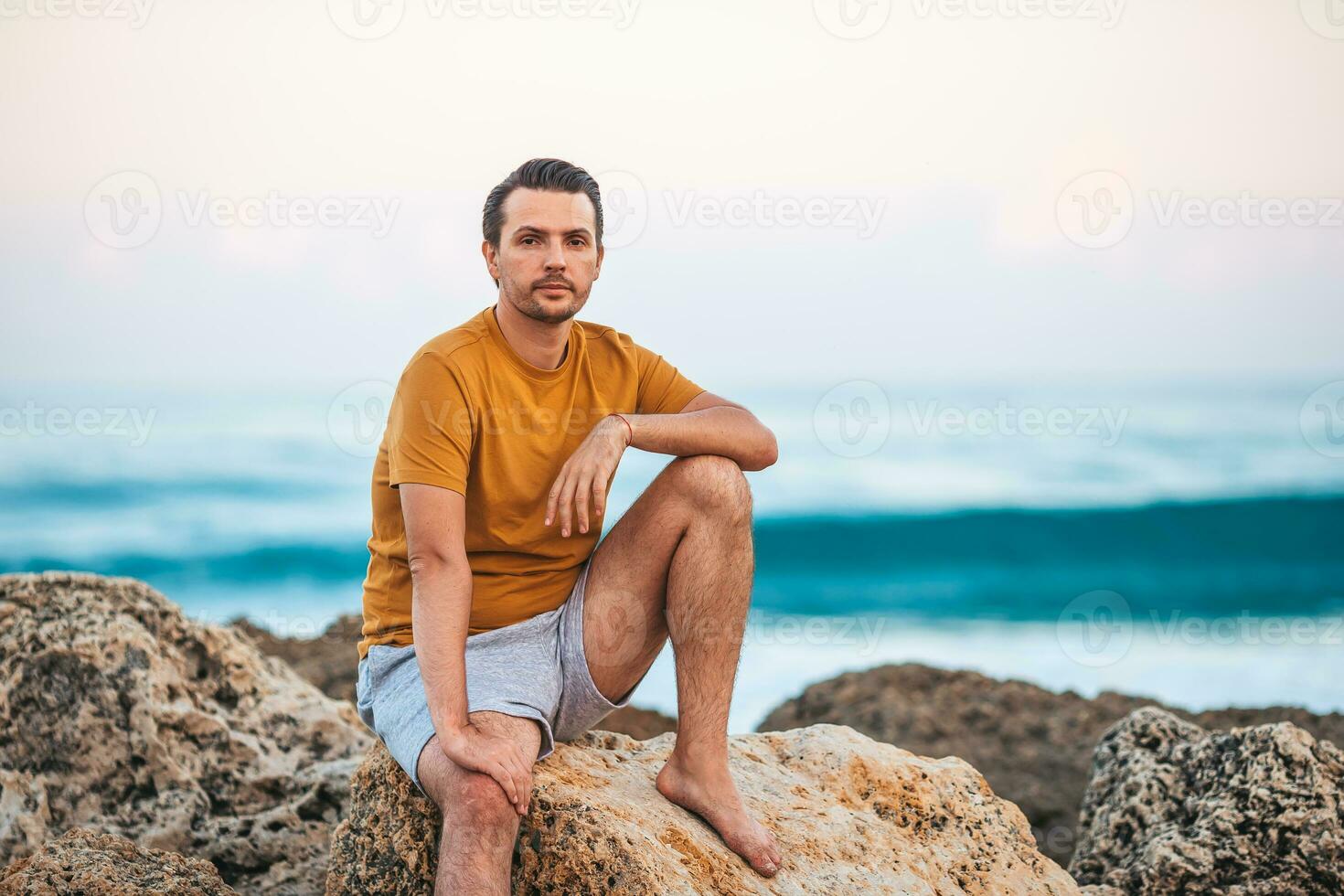 jong Mens ontspannende Aan de strand Bij zonsondergang foto