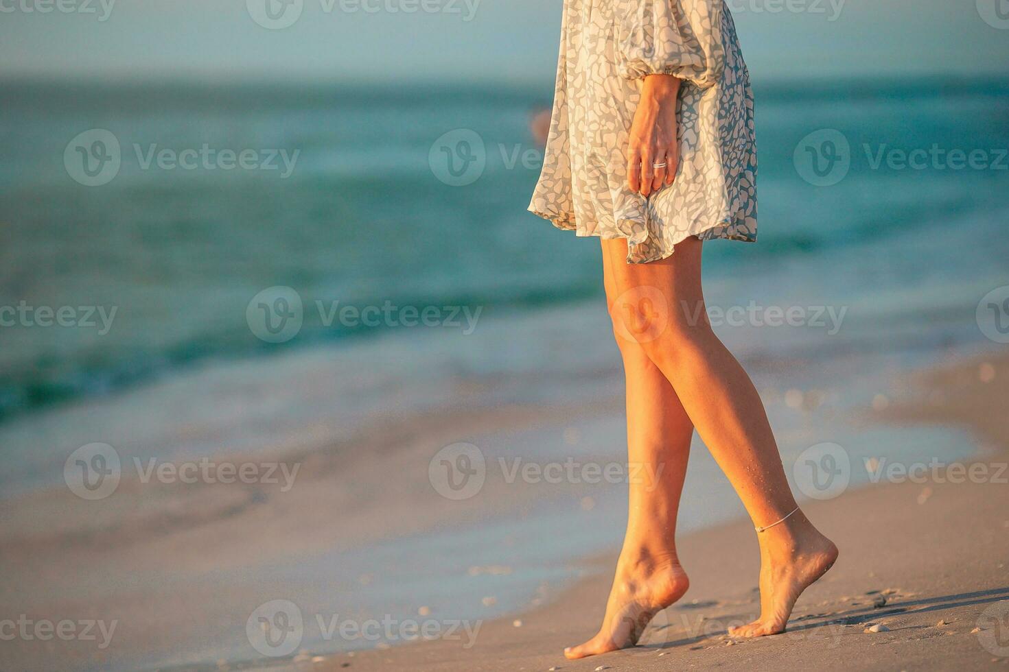 vrouw poten Aan de strand detailopname. vrouw in jurk wandelen Aan de strand foto