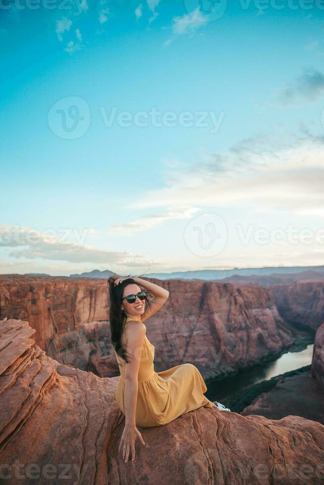 mooi vrouw in geel jurk Aan de rand van de klif Bij hoefijzer band Ravijn in paje, Arizona. avontuur en toerisme concept. mooi natuur in Verenigde Staten van Amerika foto