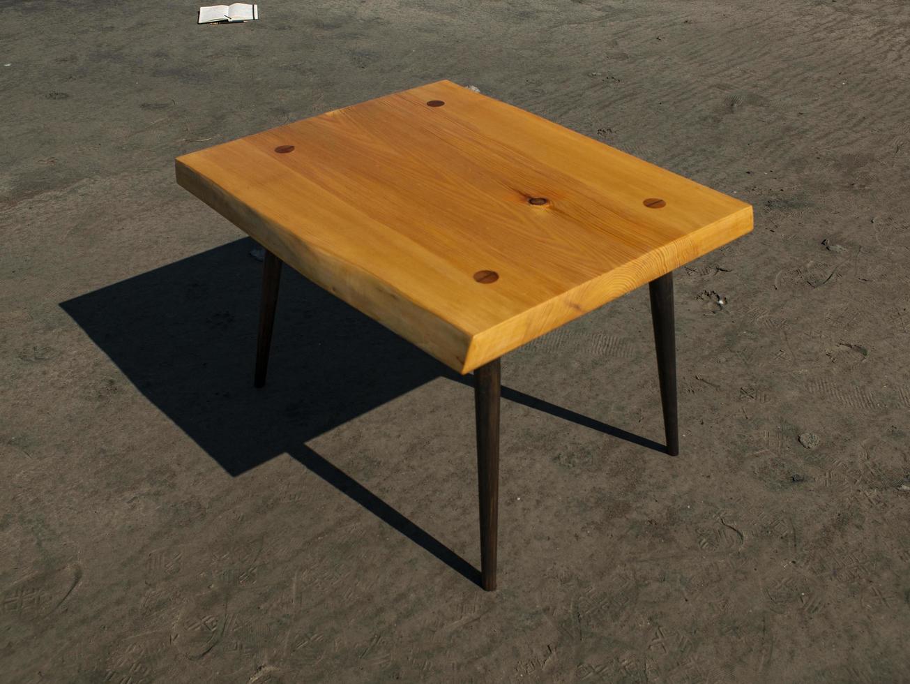 handgemaakte houten salontafel staat op het zand. ambachtelijke werk foto