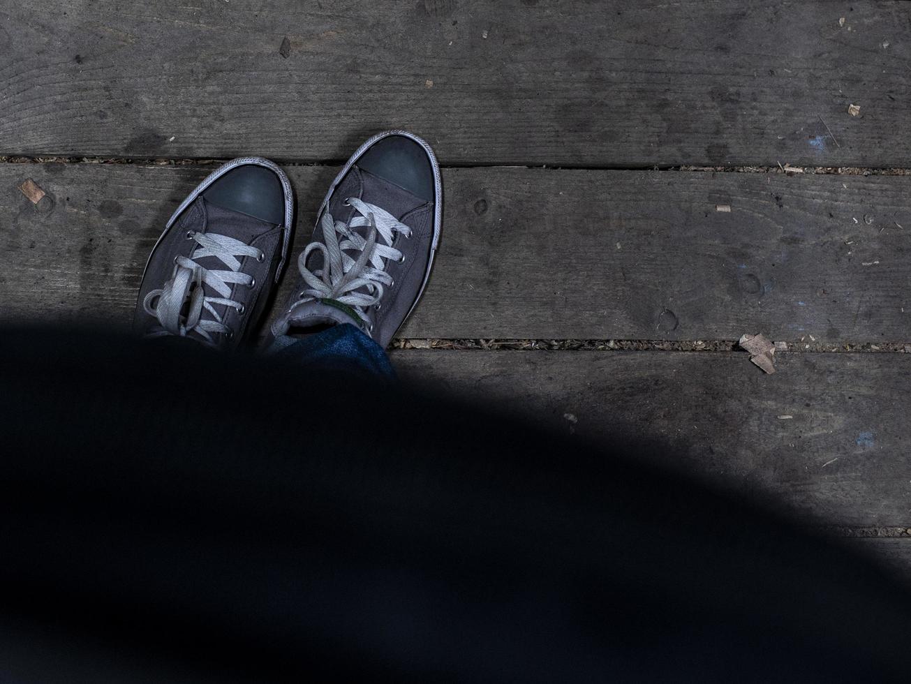 herenvoeten in sneakers staan op de houten vloer foto