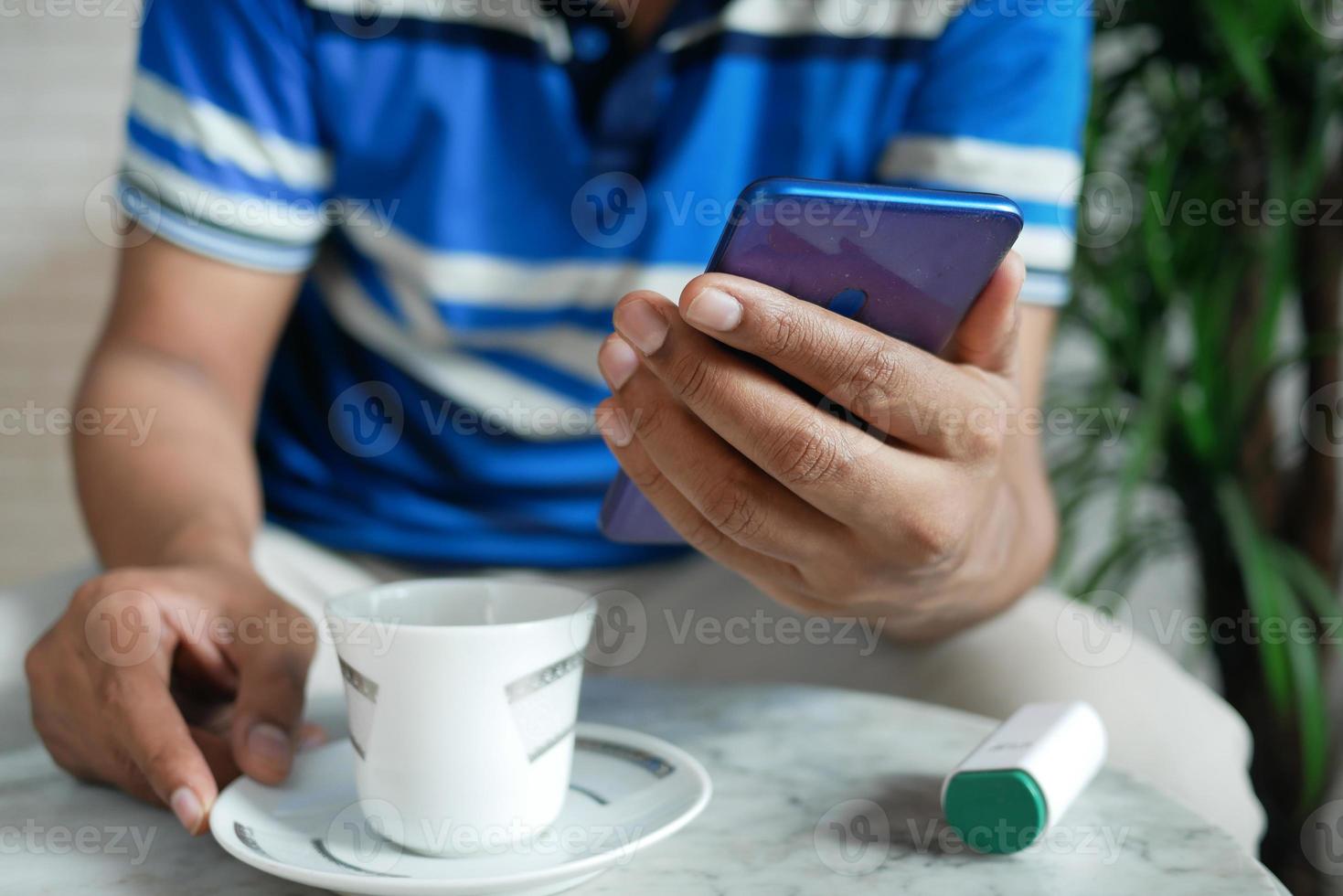 jonge man hand met behulp van slimme telefoon en het drinken van thee foto