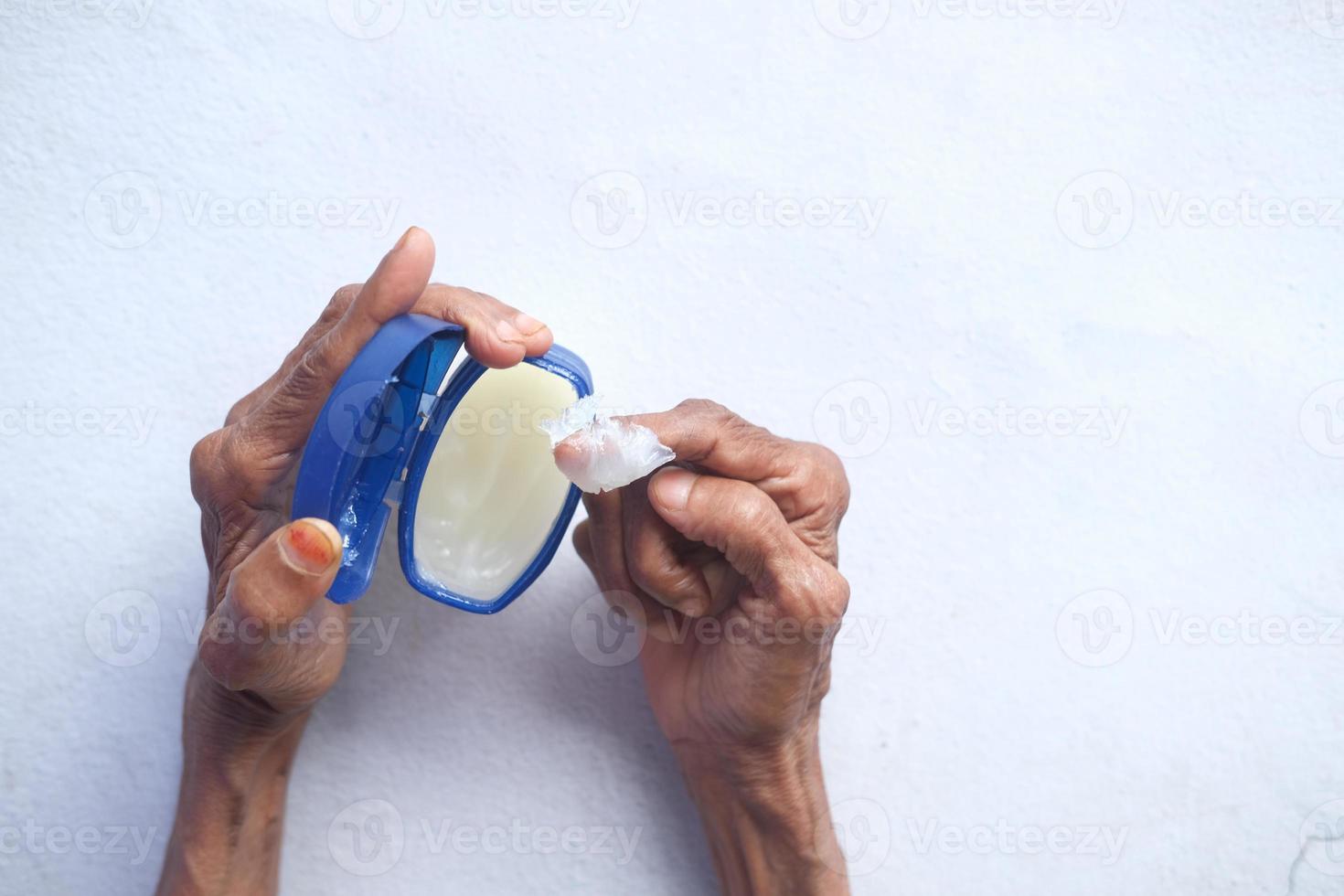 senior vrouw die vaseline op de huid gebruikt foto