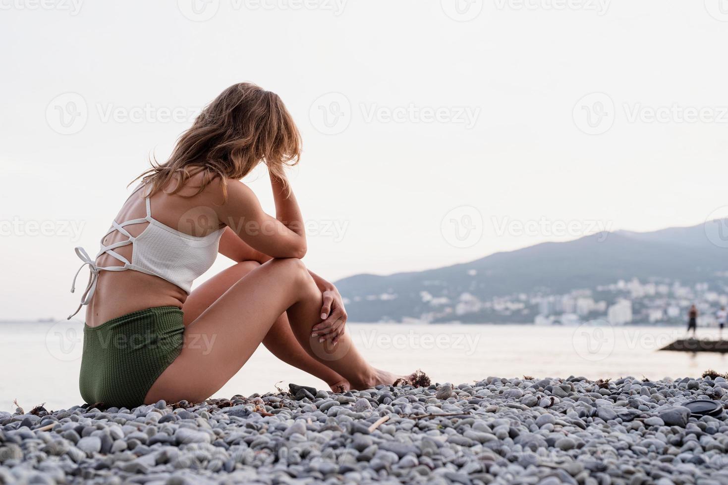 jonge, depressieve vrouw, zittende, op het strand, kijken weg, achterk bezichtiging foto