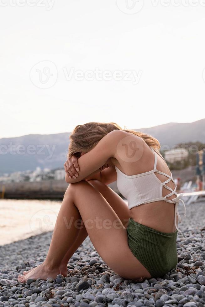 jonge depressieve vrouw zittend op het strand foto