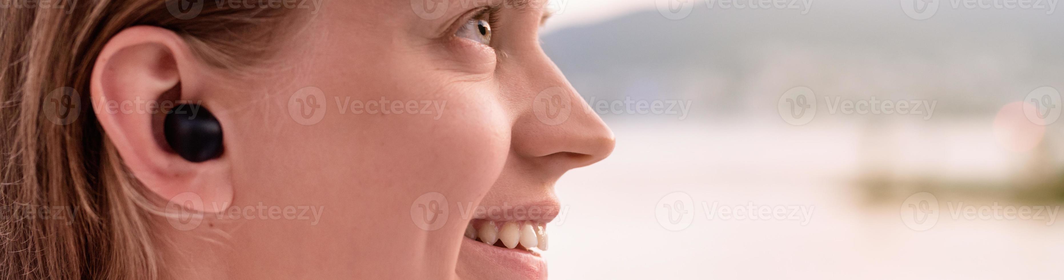 vrouw die draadloze oortjes gebruikt, kust op de achtergrond foto