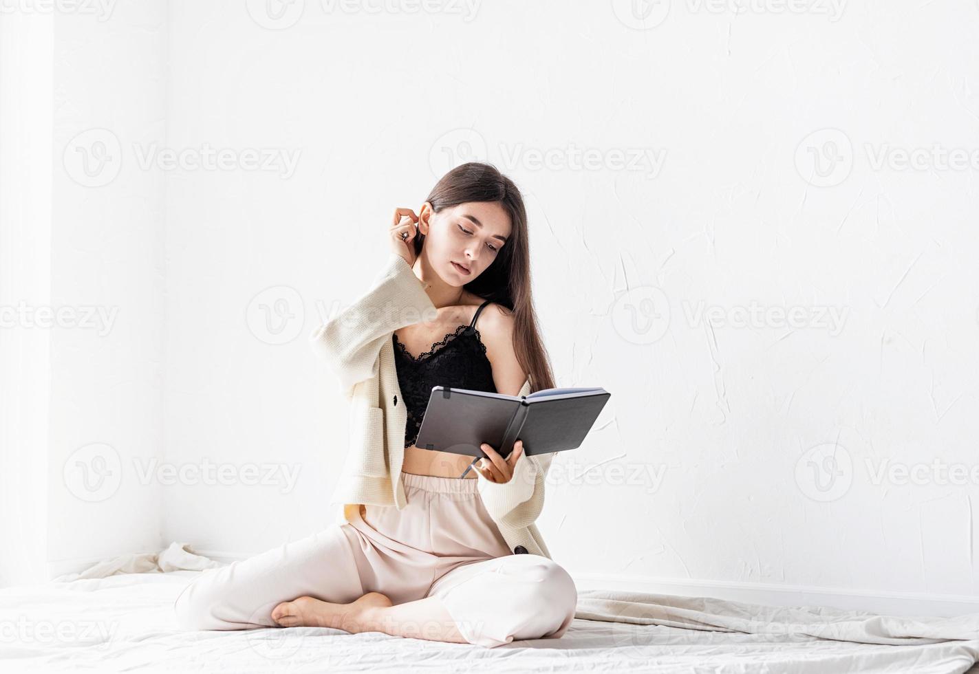 vrouw in comfortabele huiskleding die notities schrijft terwijl ze op de grond zit foto