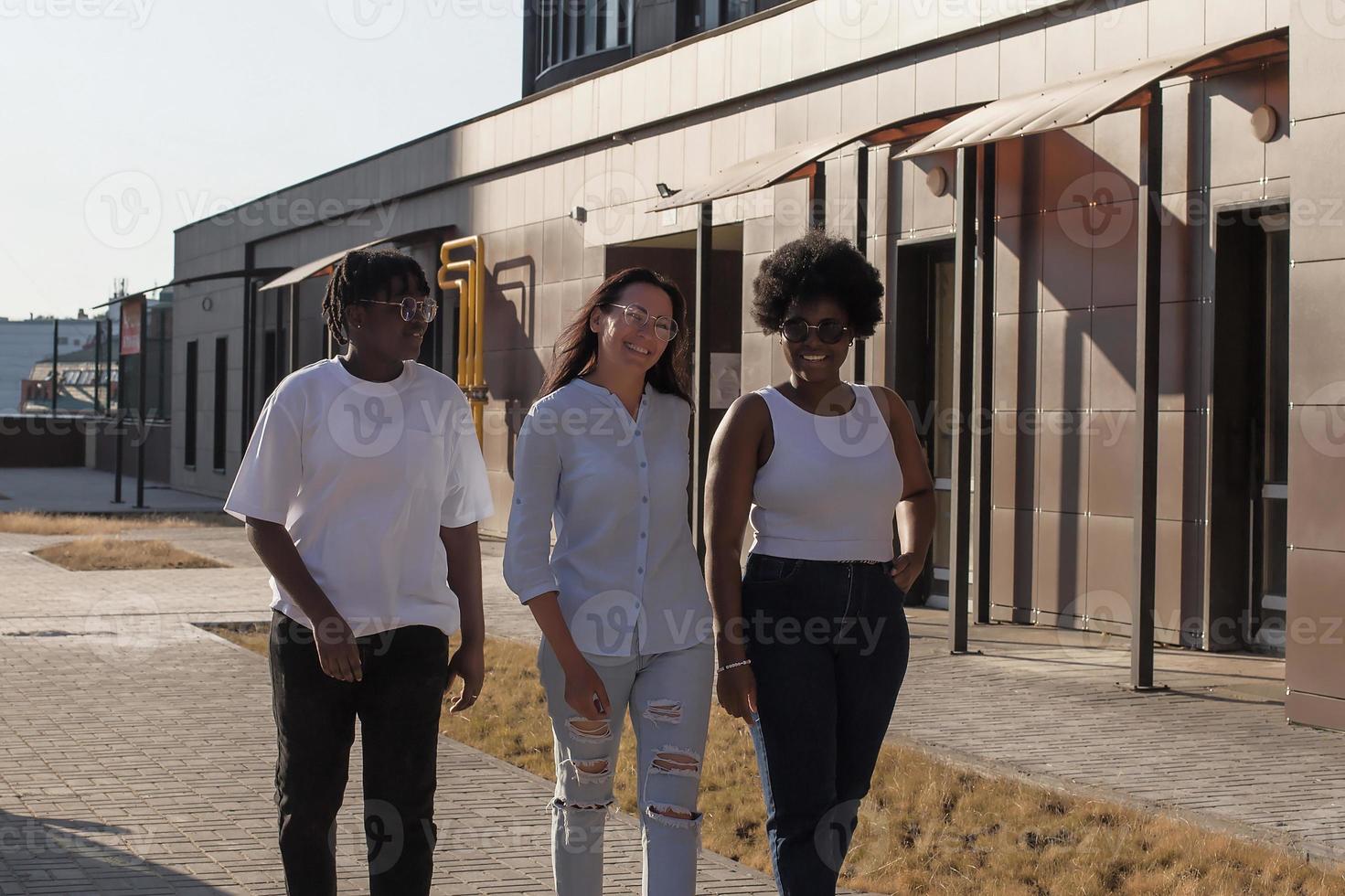 vrolijke meisjes van verschillende nationaliteiten lopen over straat foto