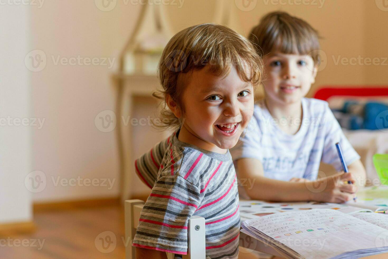 twee kinderen zittend Bij een tafel met een pen en papier foto