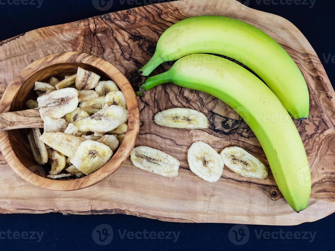 gedroogde bananenchips op olijfhout foto