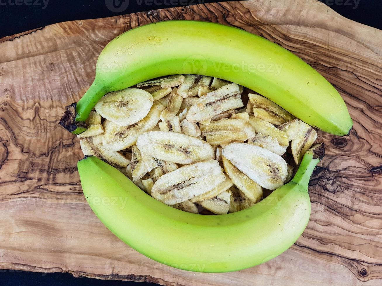 gedroogde bananenchips op olijfhout foto