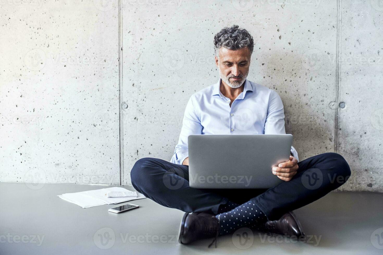 volwassen zakenman zittend Aan de verdieping gebruik makend van laptop foto