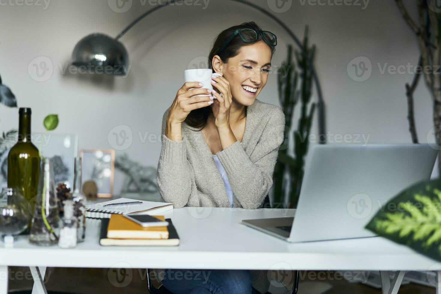 gelukkig jong vrouw Bij huis met laptop Aan bureau foto