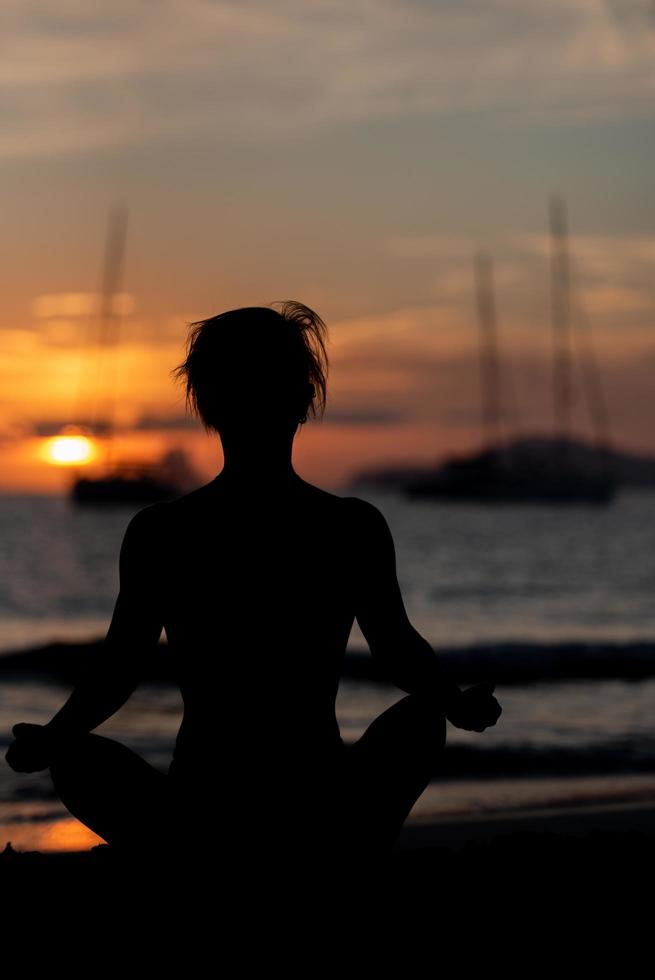 silhouet van fitnessmodel dat yoga doet bij zonsondergang foto