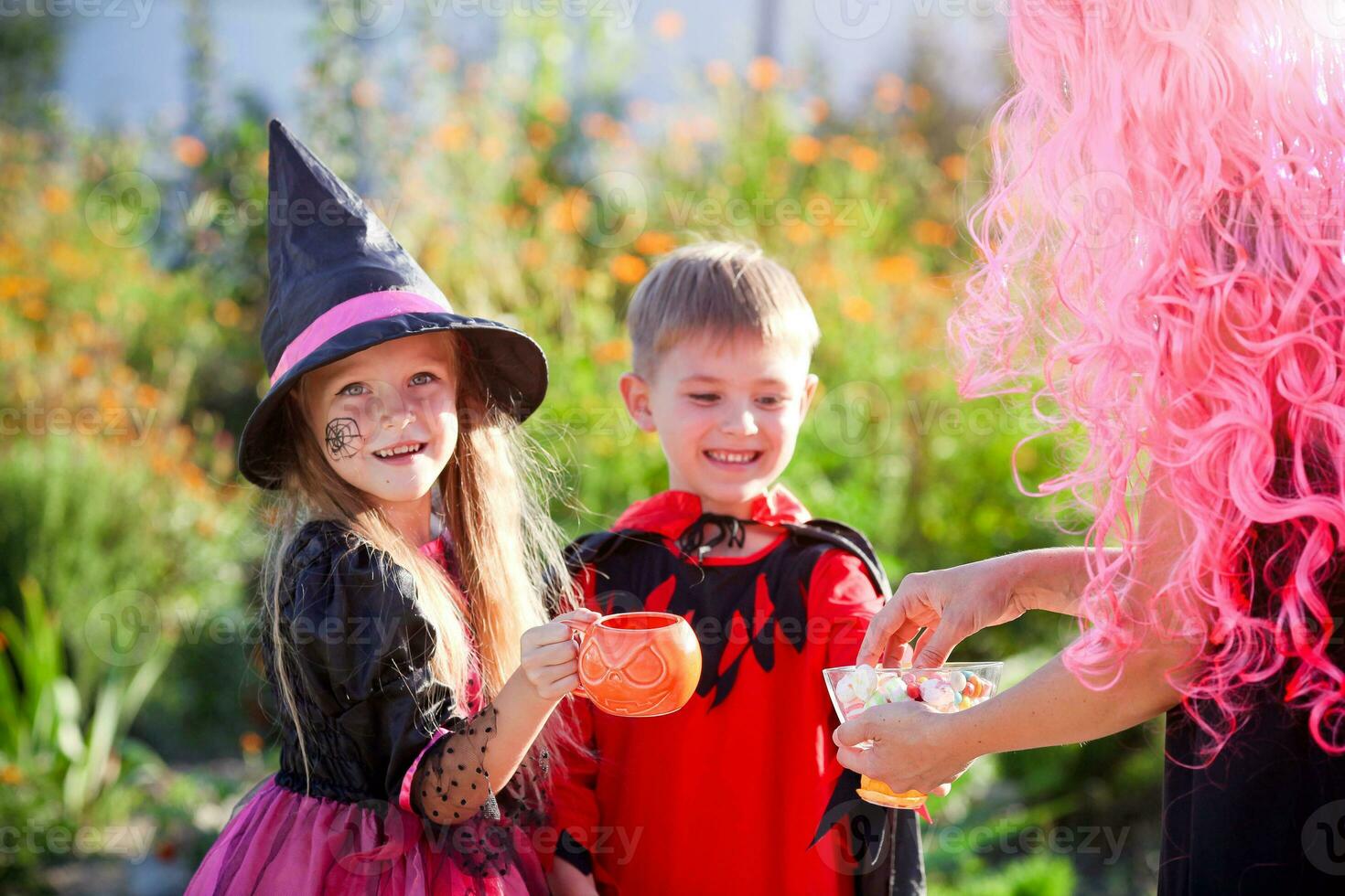 kinderen truc of traktatie in halloween kostuum . een weinig jongen en een meisje in pakken te ontvangen snoep van een vrouw . foto
