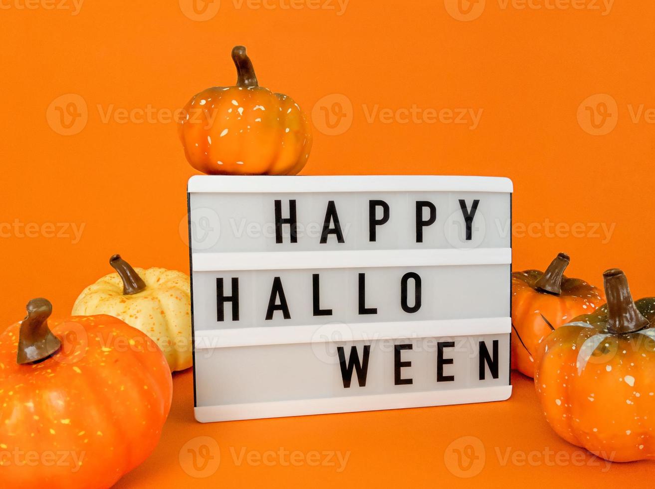 lightbox met happy halloween-uitdrukking en pompoenen op oranje achtergrond foto