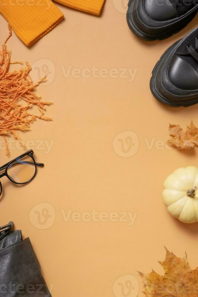 vrouw schoenen met herfst bladeren en pompoen Aan oranje achtergrond met kopiëren ruimte top visie, vlak leggen foto