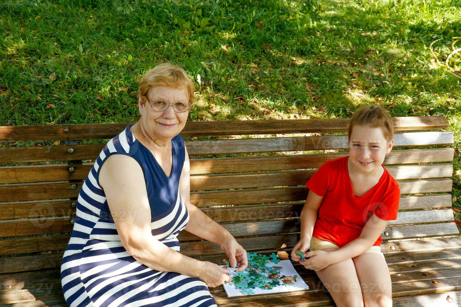 grootmoeder en kleindochter in de park Aan een bank verzamelen puzzel foto