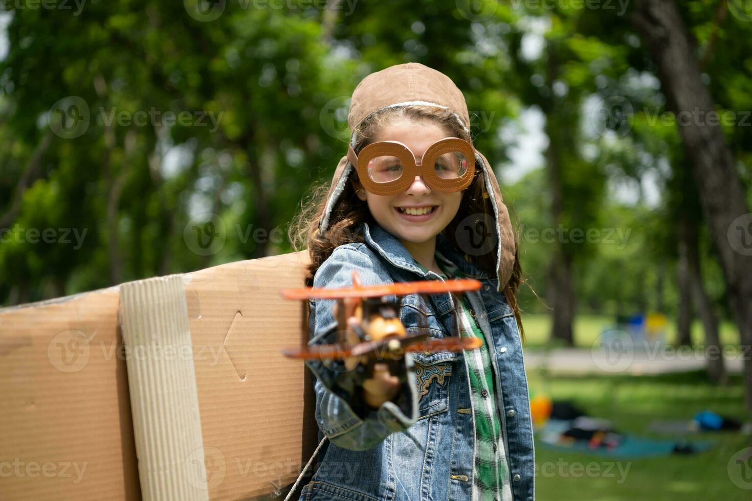 een weinig meisje Aan vakantie Bij de park met een piloot kleding en vliegend apparatuur. rennen in de omgeving van en hebben pret met haar dromen. foto