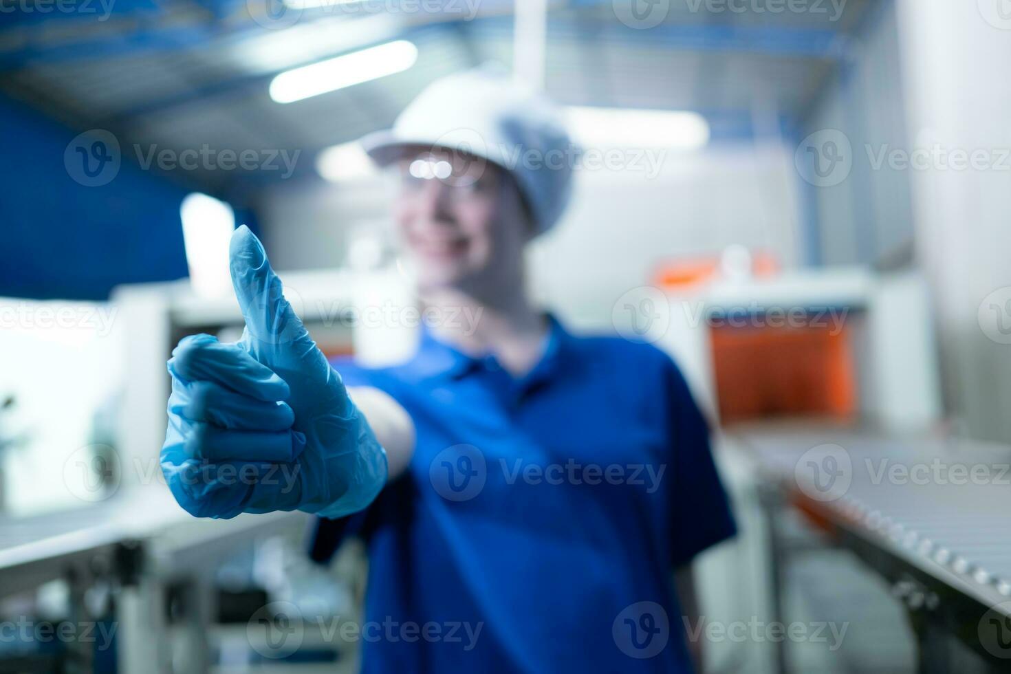 portret van gelukkig vrouw fabriek arbeider tonen duimen omhoog gebaar in drinken water fabriek foto