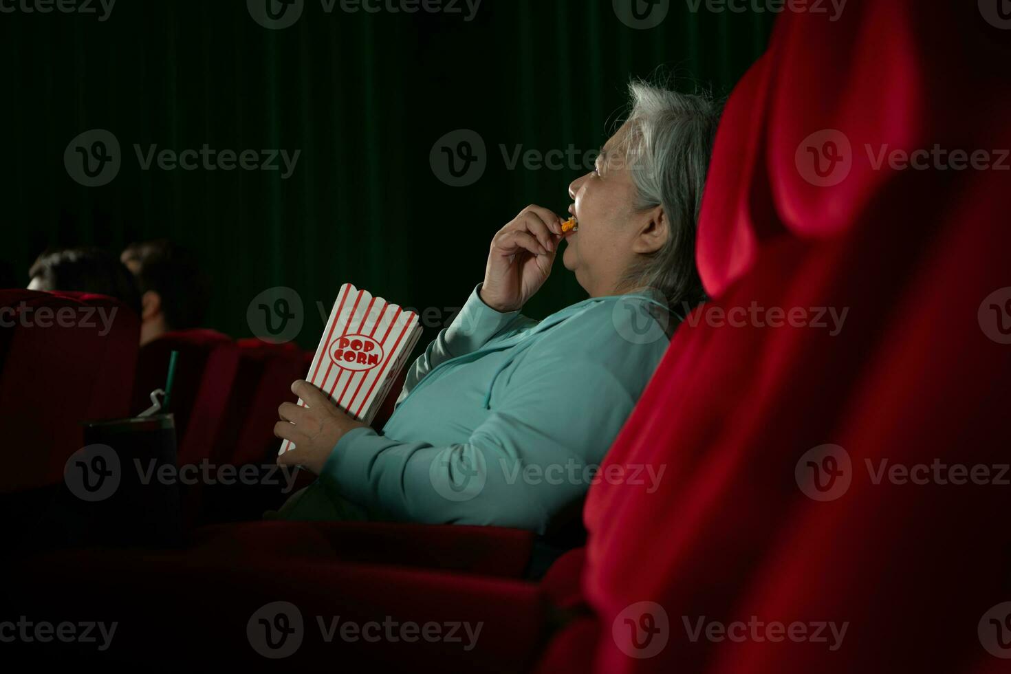 Aziatisch senior vrouw aan het kijken film Bij de bioscoop in de avond tijd. foto