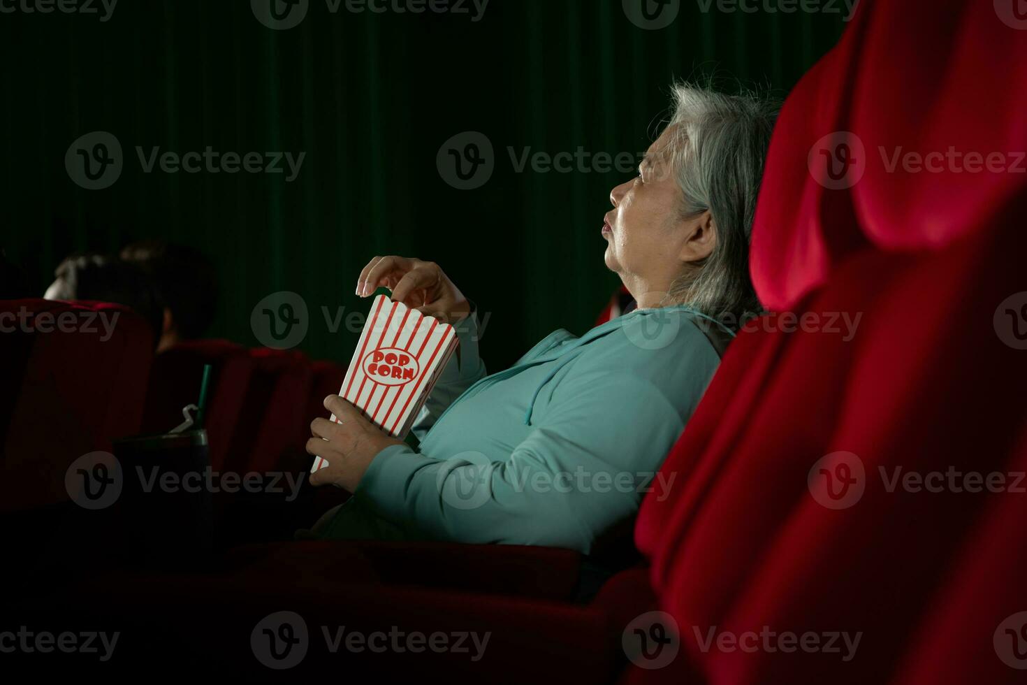 Aziatisch senior vrouw aan het kijken film Bij de bioscoop in de avond tijd. foto