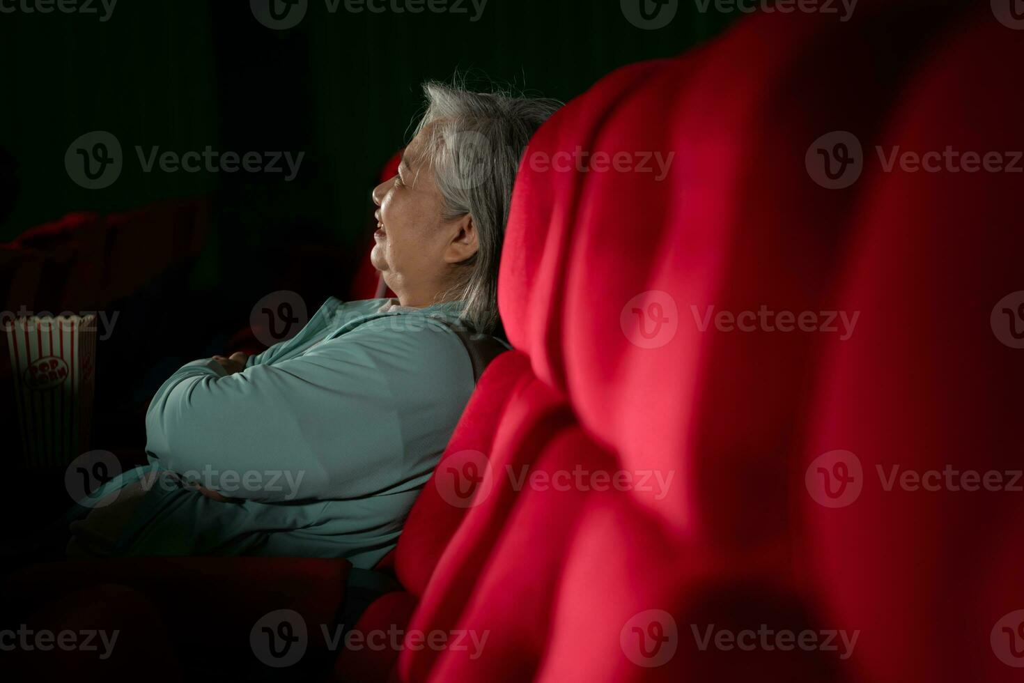 Aziatisch senior vrouw aan het kijken film Bij de bioscoop in de avond tijd. foto