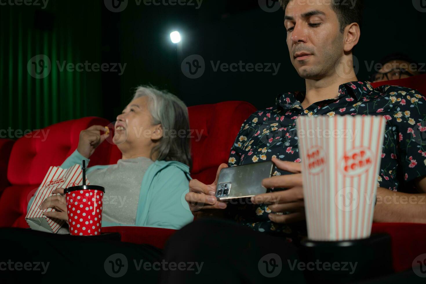 een jong Mens was heimelijk opname een film in een film theater terwijl aan het kijken een film foto