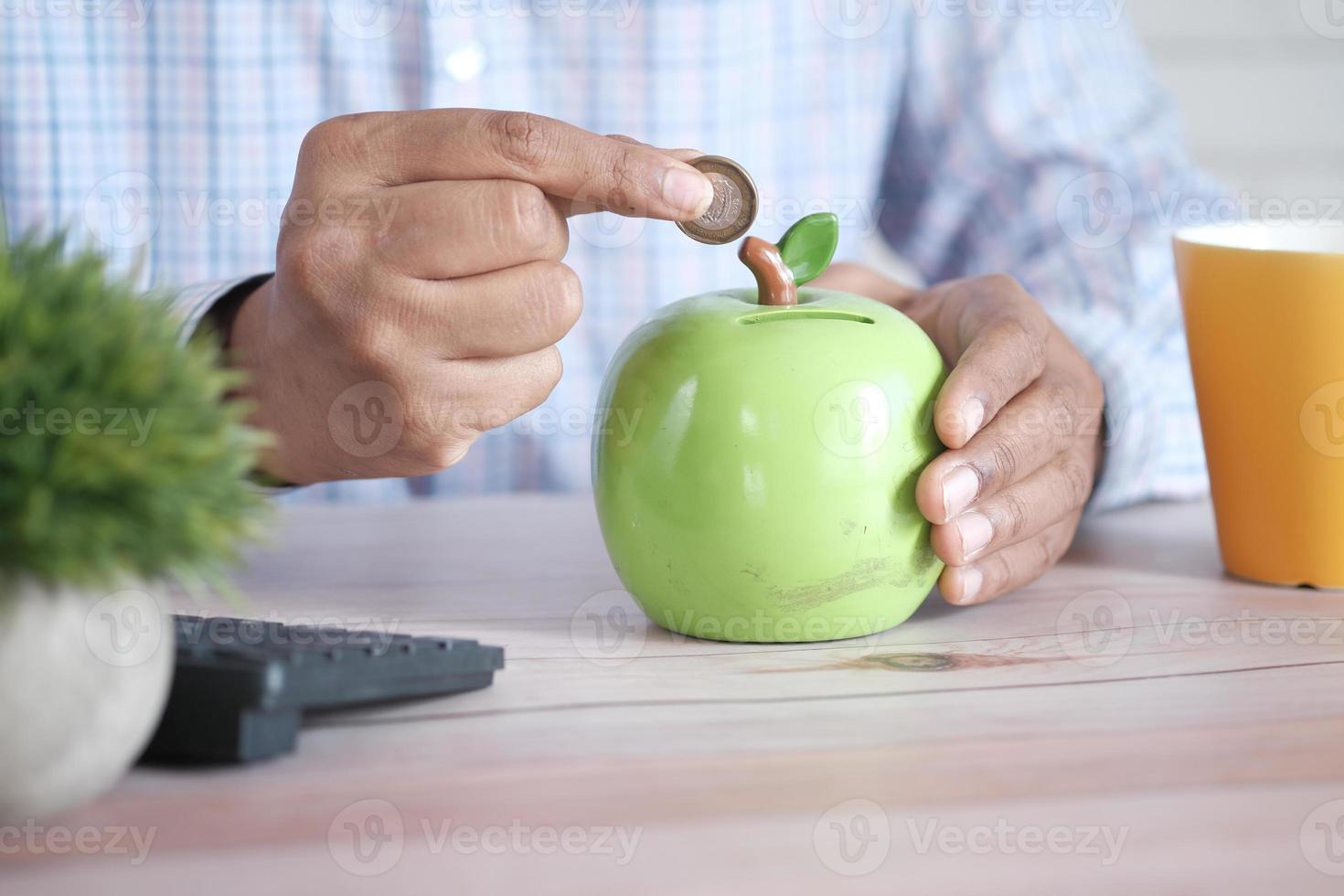 jonge man spaart munten in een witte pot foto