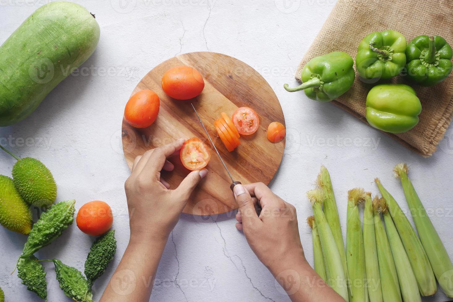 hand van persoon die tomaten snijdt op snijplank foto