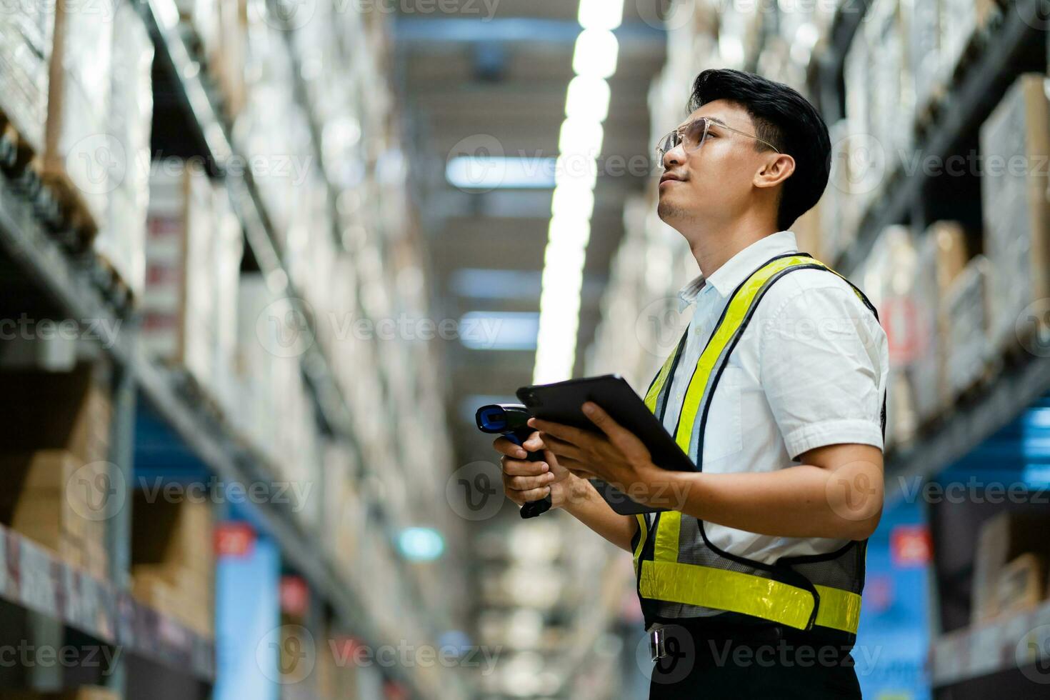 een Aziatisch magazijn manager toepassingen een tablet computer naar inspecteren goederen in een magazijn. logistiek en exporteren bedrijf concept. foto