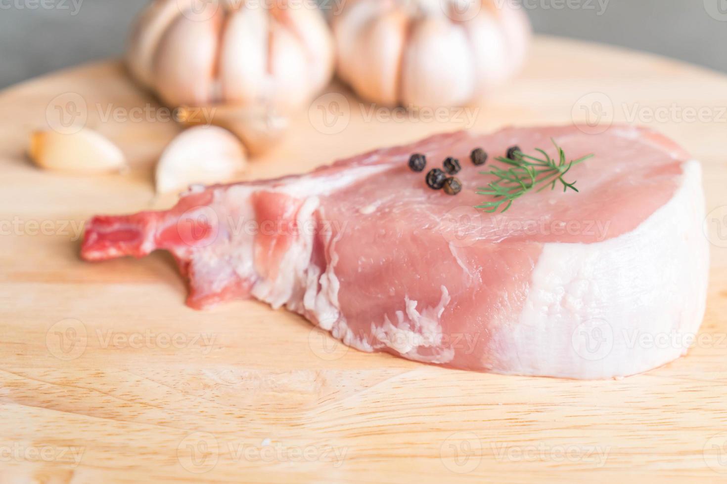 verse karbonade op een houten bord met knoflook en zwarte pepers foto