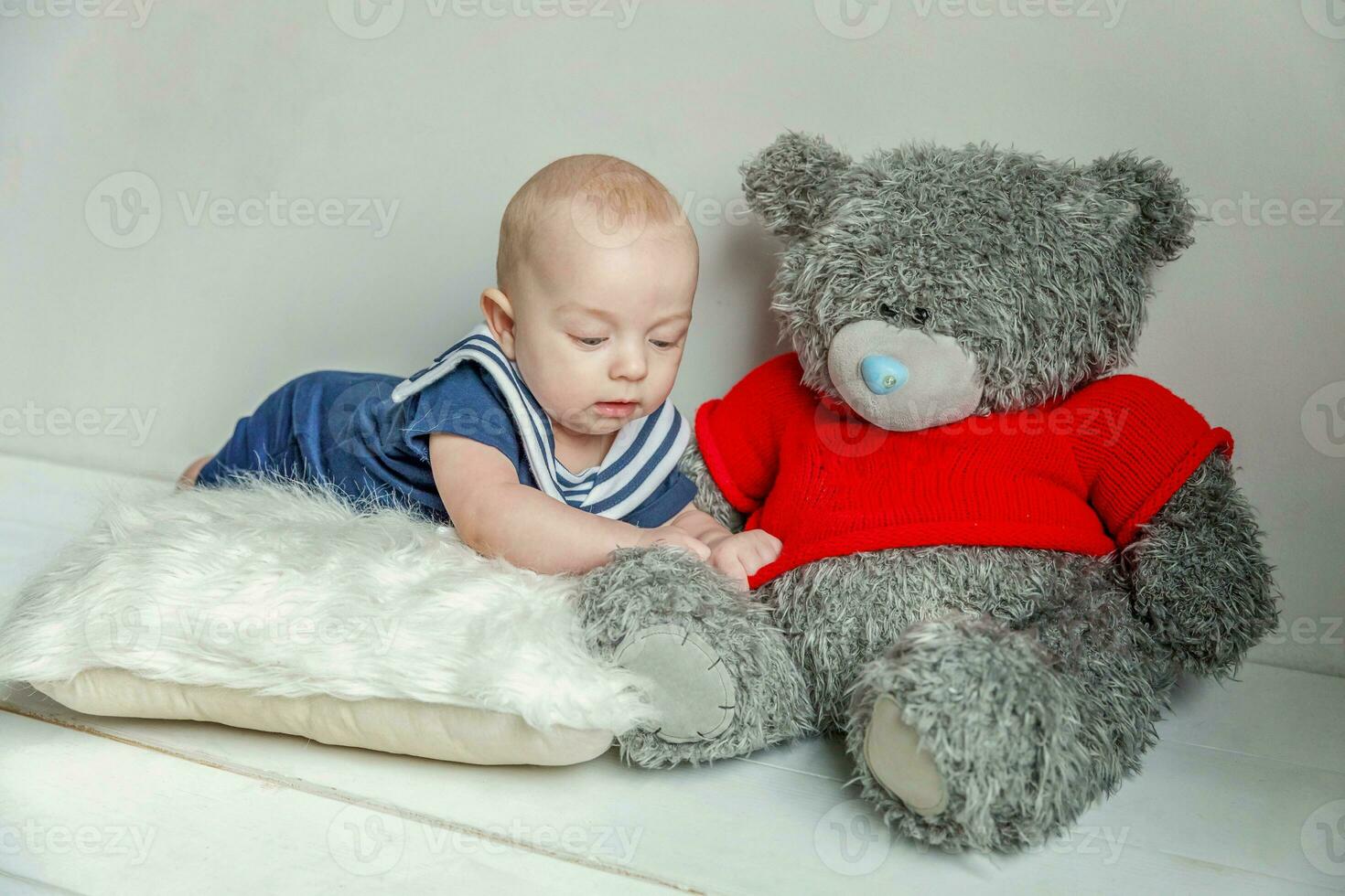 zuigeling baby jongen leugens Aan hoofdkussen met teddy beer speelgoed- Aan wit slaapkamer achtergrond foto