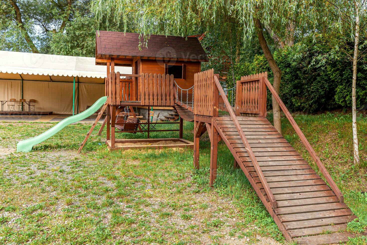 lege moderne houten kinderspeelplaats ingesteld op groene tuin in openbaar park in zomerdag. grappig speelgoedland voor kinderen. stedelijke bewegingsactiviteiten voor kinderen buitenshuis. buurt jeugd concept. foto